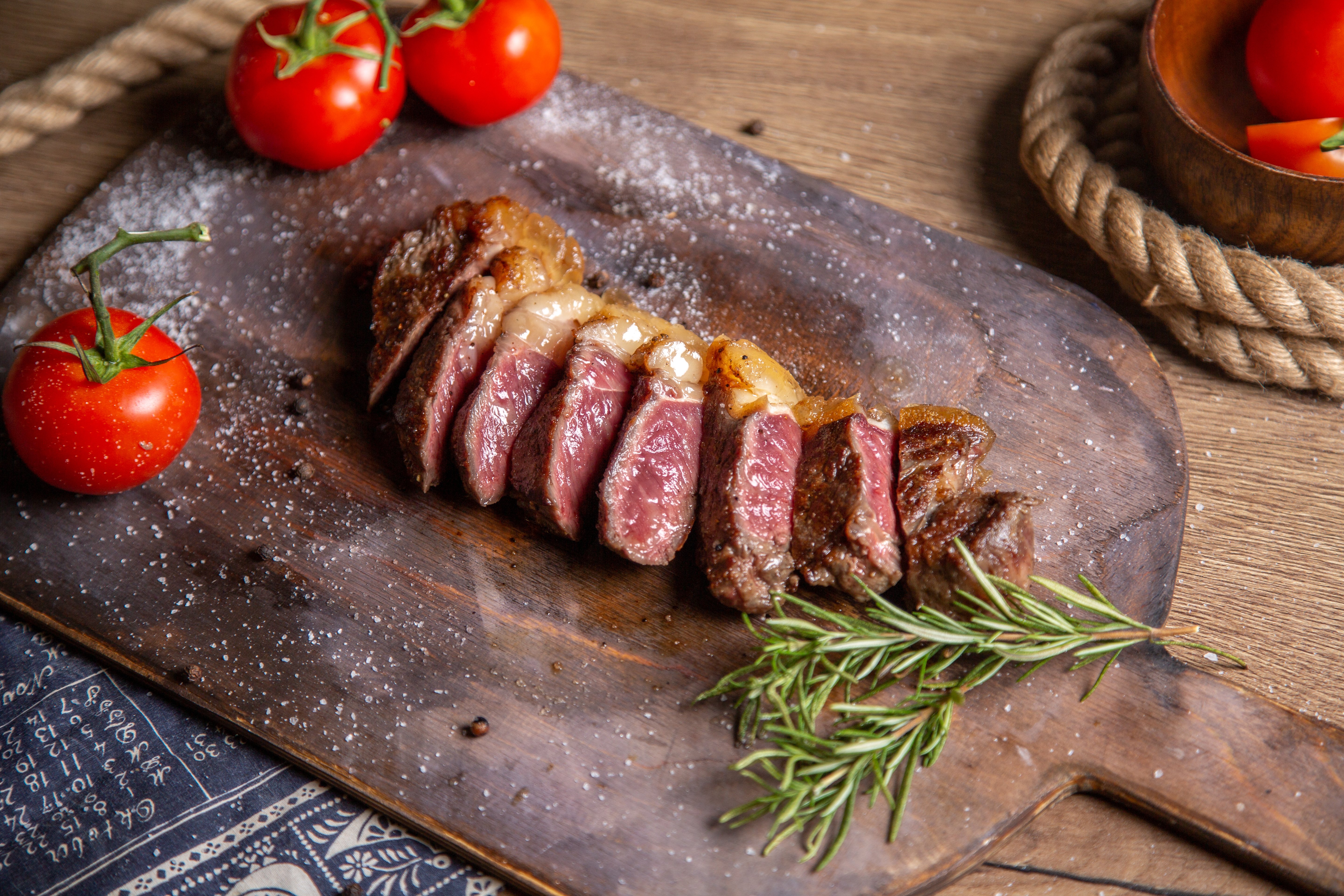 vista-frontal-de-carne-fatiada-frita-com-verduras-e-tomates-vermelhos-frescos-na-mesa-de-madeira